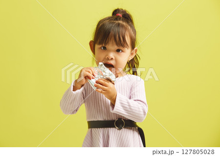 Little asian girl biting large of chocolate with pleased joyful look and pleasure expression having love to sugar. Little asian girl biting large of chocolate with pleased joyful look and pleasure expression having love to sugar. 127805028