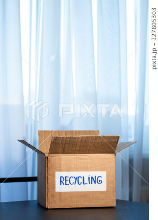 Woman prepared cardboard box full of used outfits for recycling. Responsible disposal and secondhand fashion concept. 127805303