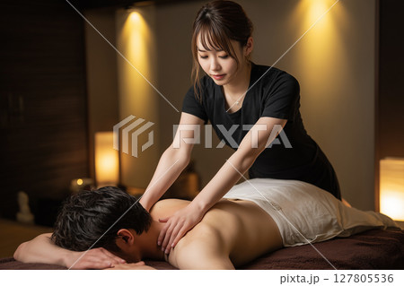 メンズエステで男性の肩をほぐす若い女性スタッフ 127805536