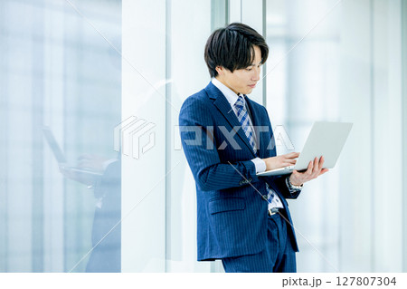 オフィスでノートパソコンを持つ若いビジネスマン 127807304
