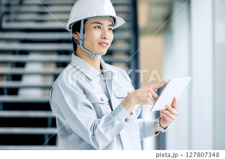 オフィスの廊下に立つ作業服の若い作業員 オフィスの廊下に立つ作業服の若い作業員 127807348