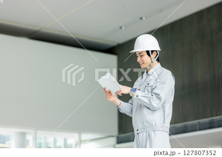 オフィスの廊下に立つ作業服の若い作業員 127807352