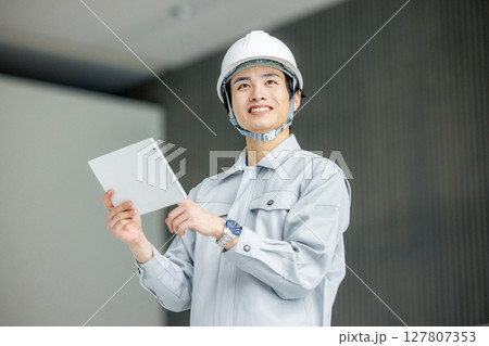 オフィスの廊下に立つ作業服の若い作業員 127807353