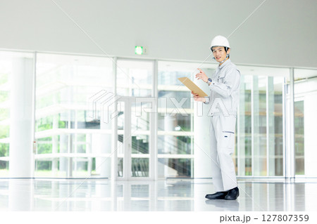 オフィスの廊下に立つ作業服の若い作業員 オフィスの廊下に立つ作業服の若い作業員 127807359