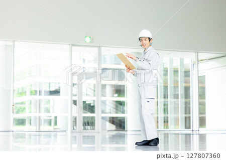 オフィスの廊下に立つ作業服の若い作業員 127807360
