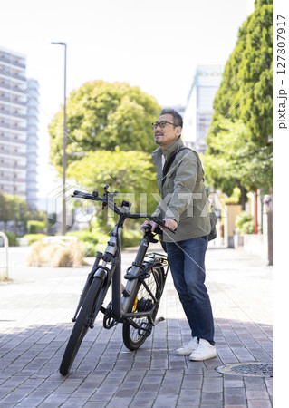 自転車で移動する50代後半の男性 127807917