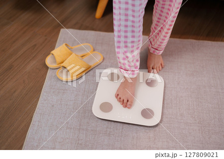 Daily wellness routine adult monitoring body weight on smart scale for longevity health tracking and fitness goals at home Daily wellness routine adult monitoring body weight on smart scale for longevity health tracking and fitness goals at home 127809021