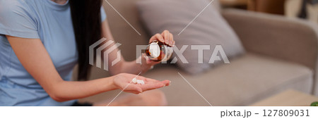 Asian Young Adult Woman's Hands Taking Daily Supplements for Optimal Health and Wellness at Home Promoting Longevity Lifestyle 127809031