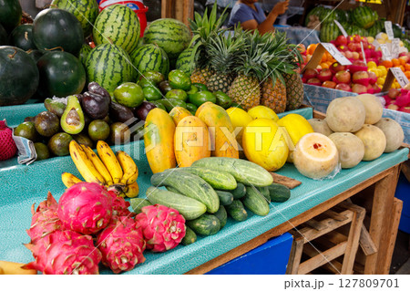 Tropical fruits including watermelon, pineapple, papaya, dragon fruit, and cucumbers at market stall in Philippines 127809701