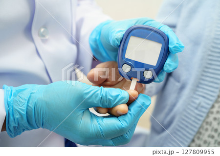 Asian doctor using digital glucose meter for check sample blood sugar level to treatment diabetes. 127809955