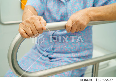 Asian elderly woman patient use toilet support rail in bathroom. Asian elderly woman patient use toilet support rail in bathroom. 127809987
