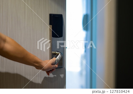 A woman opens an electronic lock with a card and enters a hotel room. A woman opens an electronic lock with a card and enters a hotel room. 127810424