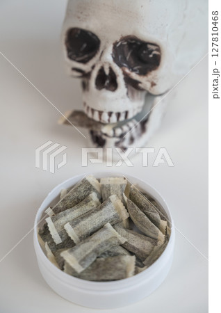 Skull Chewing Tobacco on a White Table. Skull Chewing Tobacco on a White Table. 127810468