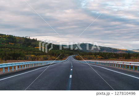A long, open highway leads through a picturesque mountainous area. A long, open highway leads through a picturesque mountainous area. 127810496