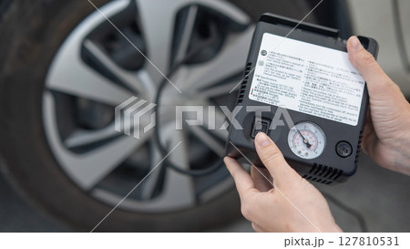 Woman holding a car tire pump.  127810531