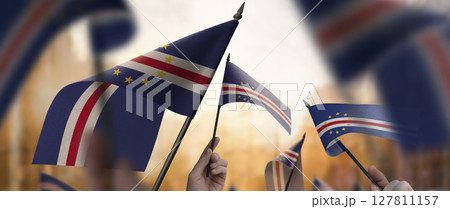 Cape Verde flags in their hands on a blurred urban background 127811157