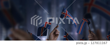Iceland flags in their hands on a blurred urban background Iceland flags in their hands on a blurred urban background 127811167