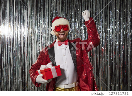 Happy funny man in Santa Claus costume holding present gift box celebrating New Year and Christmas 127811721