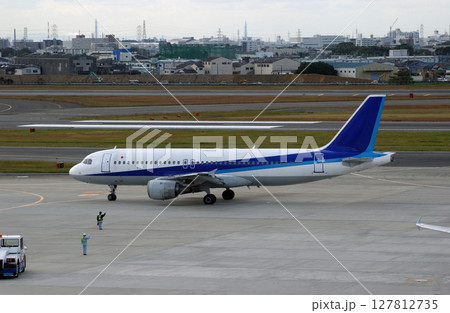 出発する飛行機に手を振るグランドスタッフ 127812735