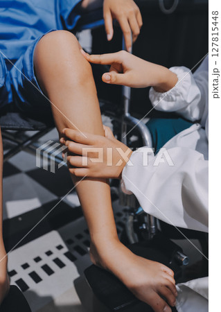 Physiotherapist checking knee of female patient stock Physiotherapist checking knee of female patient stock 127815448