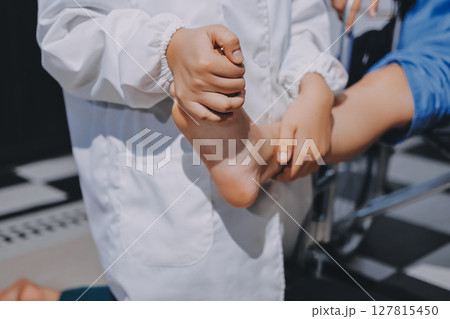 Physiotherapist checking knee of female patient stock Physiotherapist checking knee of female patient stock 127815450