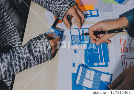 Group of young application developers analyzing uxui mobile app templates during a working meeting 127815469