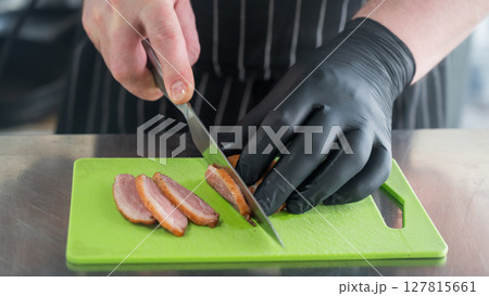 The chef slices the roast duck.  127815661