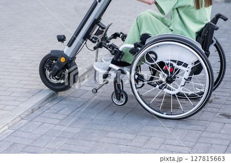 A faceless woman in a wheelchair with an assistive device for manual control. Electric handbike.  127815663