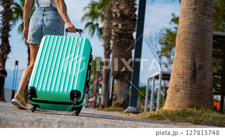 A Caucasian woman walks with a suitcase to the coast. A Caucasian woman walks with a suitcase to the coast. 127815748