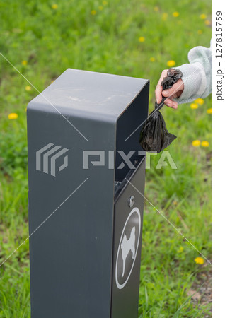 Responsible Dog Owner Disposing of Waste in Park Bin. Responsible Dog Owner Disposing of Waste in Park Bin. 127815759