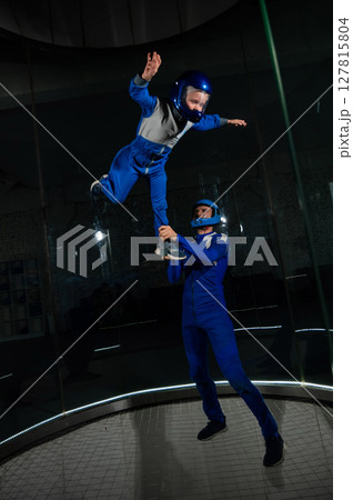 A man teaches a boy to fly in a wind tunnel. Lack of gravity. 127815804