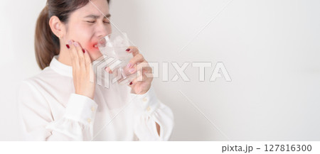 Business woman having toothache and pain after drink ice water for concept of Teeth Sensitive to Cold, Tooth Decay and Gum Disease, Grinding Teeth and Stress, Exposed Nerve Roots, Crack and Receding 127816300