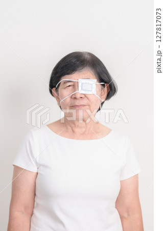 Elderly Woman with Eye protecting by Eye Pad for concepts of Eye disease, Cataract, Glaucoma, Age Related Macular Degeneration, Diabetic Retinopathy, Vitreous, Conjunctivitis, World Glaucoma day 127817073