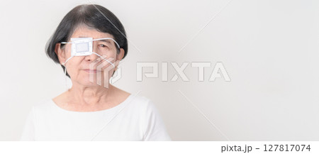 Elderly Woman with Eye protecting by Eye Pad for concepts of Eye disease, Cataract, Glaucoma, Age Related Macular Degeneration, Diabetic Retinopathy, Vitreous, Conjunctivitis, World Glaucoma day 127817074