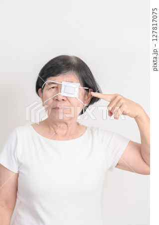 Elderly Woman with Eye protecting by Eye Pad for concepts of Eye disease, Cataract, Glaucoma, Age Related Macular Degeneration, Diabetic Retinopathy, Vitreous, Conjunctivitis, World Glaucoma day 127817075