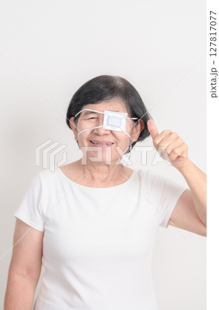 Elderly Woman with Eye protecting by Eye Pad for concepts of Eye disease, Cataract, Glaucoma, Age Related Macular Degeneration, Diabetic Retinopathy, Vitreous, Conjunctivitis, World Glaucoma day 127817077