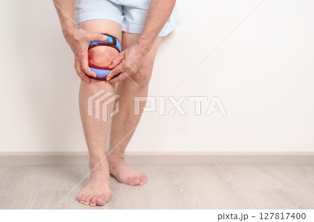 Elderly woman having knee ache with knee support brace for concepts of Runners Knee or Patellofemoral Pain Syndrome, osteoarthritis, arthritis, rheumatism and Patellar Tendinitis. Senior health care 127817400