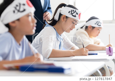 必勝の鉢巻をして塾で勉強する子供達 127817847