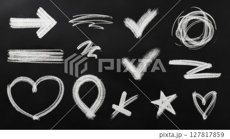 Chalk marks display various symbols such as arrows, check marks, hearts, and stars scattered across a black surface, showcasing creativity and fun in a classroom or artistic environment. 127817859