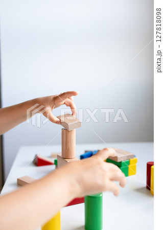 Child building with colorful blocks on white table 127818098
