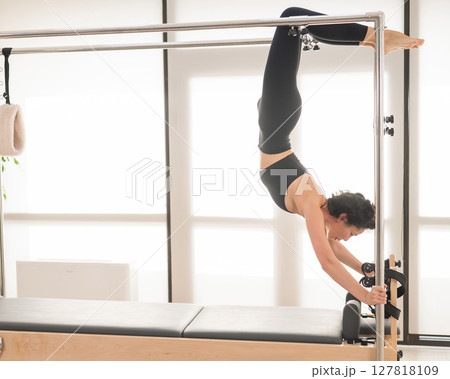 Asian woman doing pilates on reformer. Asian woman doing pilates on reformer. 127818109