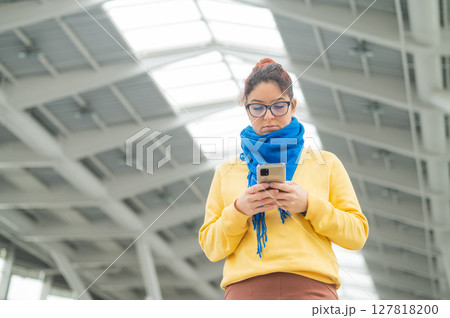 Caucasian woman using smartphone in public place.  127818200