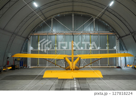 Yellow airplane glider in the hangar.  127818224
