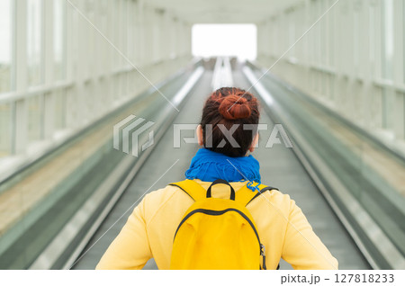 Rear view of a woman with a backpack moving on a travolator 127818233