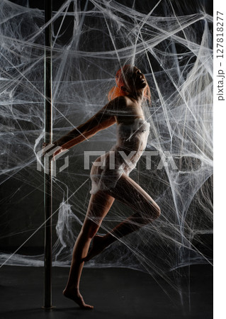 Red-clad woman entangled in a net trap amidst a dark, web-like backdrop Red-clad woman entangled in a net trap amidst a dark, web-like backdrop 127818277