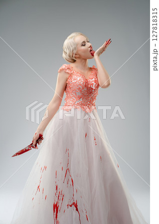 Dramatic portrayal of a bride in a blood-splattered gown in the studio 127818315