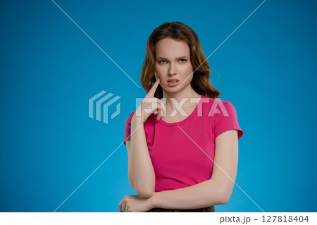 Woman expressing various emotions while posing in a studio with a bright blue background during a photoshoot 127818404