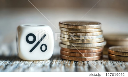 Stack of coins with different colors and sizes, next to a white dice showing percentage symbol, representing interest rate, investment growth, and financial success 127819062
