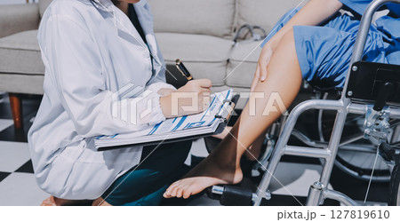 Physiotherapist checking knee of female patient stock Physiotherapist checking knee of female patient stock 127819610
