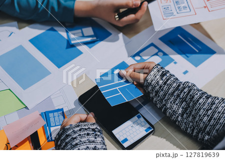 Group of young application developers analyzing uxui mobile app templates during a working meeting 127819639